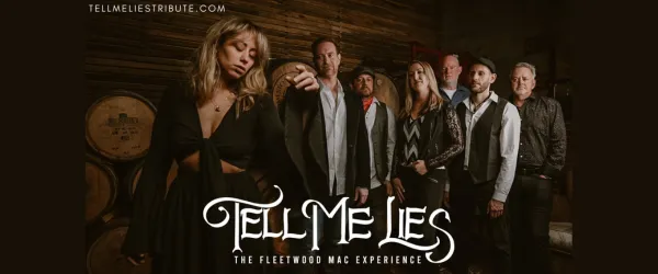 Seven band members of Tell Me Lies pose in front of wooden barrels under their logo and website.